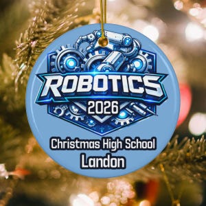 May include: A round, light blue ceramic ornament featuring a central graphic of mechanical gears and robotic arms. The text reads ROBOTICS 2026, Christmas High School, and Landon. A gold string is attached to the top for hanging on a tree.