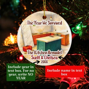 May include: A round ceramic ornament featuring an illustration of a kitchen remodel with orange cabinets, a teal island, and a red toolbox. The text reads: The Year We Survived, The Kitchen Remodel, Scott & Chelsea, 20XX. It hangs by a gold string.