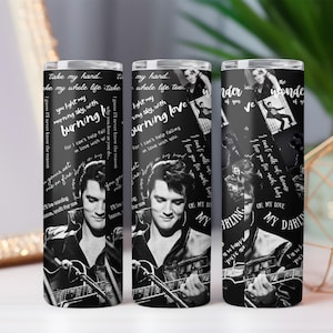 May include: Three black and white tumblers featuring Elvis Presley. The tumblers have images of Elvis playing guitar, song lyrics, and the words "Burning Love" and "My Darling". The tumblers are cylindrical and appear to be made of stainless steel.