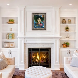 May include: A framed painting of a woman with dark hair and a blue dress, surrounded by flowers and stars. The painting is in a white room with a fireplace and white shelves.
