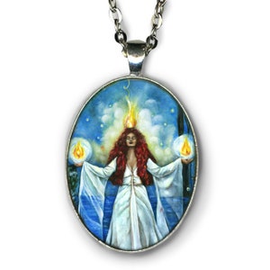 Puede incluir: Un collar con un colgante ovalado de plata, sobre un fondo azul, que representa a una mujer con cabello rojo y un vestido blanco. Ella sostiene dos orbes de luz en sus manos y una llama se encuentra sobre su cabeza.