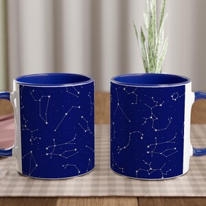 Könnte beinhalten: Zwei blaue und weiße Keramikbecher mit einem Sternenbildmuster. Die Becher haben blaue Ränder und Griffe.