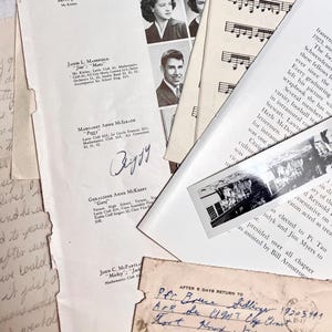 K&ouml;nnte beinhalten: Eine Sammlung von alten Papieren und Fotos, darunter ein Schwarzwei&szlig;foto eines Geb&auml;udes, eine handschriftliche Notiz mit dem Namen "Peggy", die in blauer Tinte unterschrieben ist, und eine Seite mit einer Liste von Namen und Schulclubs. Die Papiere liegen auf einer Oberfl&auml;che verstreut und bilden eine Collage von Erinnerungen.