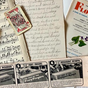 K&ouml;nnte beinhalten: Eine Sammlung von Vintage-Papierephemera, darunter eine Spielkarte, Notenbl&auml;tter und ein Leitfaden f&uuml;r bekannte amerikanische Wildblumen. Die Spielkarte ist der Bube von Herzen und ist in einem roten und wei&szlig;en Anzug. Die Notenbl&auml;tter sind f&uuml;r ein Klavier und haben ein schwarz-wei&szlig;es Design. Der Wildblumenf&uuml;hrer ist ein kleines B&uuml;chlein mit einem roten und wei&szlig;en Umschlag und zeigt eine violette Blume mit gr&uuml;nen Bl&auml;ttern. Der Text auf dem Umschlag lautet "Blume: Ein Leitfaden f&uuml;r bekannte amerikanische Wildblumen".