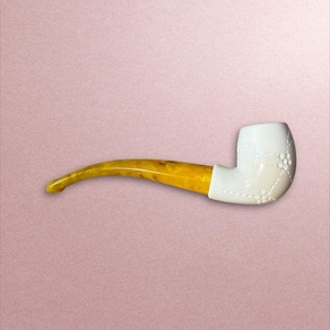 May include: A white tobacco pipe with a curved, amber-colored stem. The pipe's bowl is white with decorative stitching and floral accents. The stem is a marbled yellow and brown. The pipe is set against a pink background.