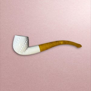 Puede incluir: Una pipa blanca con una boquilla amarilla y una cazoleta texturizada. La pipa está hecha de cerámica y tiene un diseño tradicional.