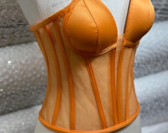 May include: Orange mesh corset with a sweetheart neckline and a satin overlay. The corset has a boned structure and a fitted silhouette.