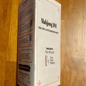 May include: A white and red Mahjong 101 guide with the text "TILES, TIPS & A LITTLE MAHJONG MAGIC". The instructor is Pam Blizzard. The guide has a red border and decorative corner designs.