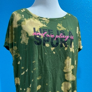 May include: Green tie-dye t-shirt with the text "Life is a Sport and we play it" in black and pink lettering.