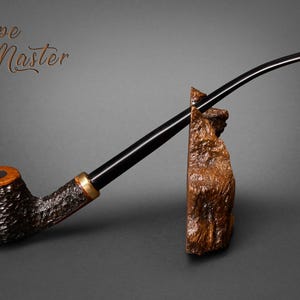 Puede incluir: Una pipa de tabaco artesanal con un cuenco oscuro y texturizado y un largo y curvado vástago negro. La pipa descansa sobre un soporte de madera. El texto "Pipe Master" es visible.