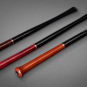May include: Three long smoking pipes with black stems and wooden bowls in dark brown, deep red, and light orange. Each pipe features a thin gold-colored metal band connecting the stem to the bowl. The text Pipe Master is visible in the upper left corner.