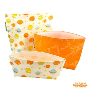 May include: Three fabric snack bags in different sizes. The largest bag has a white background with a pattern of yellow and blue planets and stars. The medium bag has an orange background with a white pattern of rockets. The smallest bag has a white background with a pattern of yellow and blue planets and stars. The text "The Original SnackSleeve PDF Pattern" is visible at the bottom of the image.