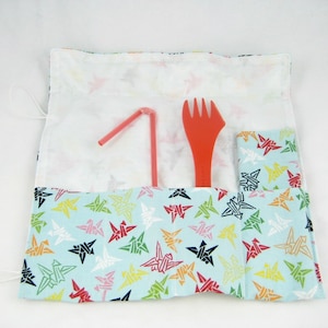 May include: A blue fabric pouch with a white lining and a colorful origami crane pattern. The pouch has a red straw, a red plastic fork, and a utensil holder inside.