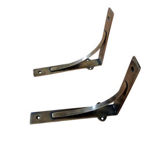 Può includere: Due staffe per mensole in ottone antico con un design curvo. Le staffe sono in metallo e hanno una finitura anticata.