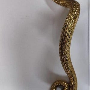May include: A golden-colored, snake-shaped decorative handle. The handle is intricately detailed with scales and a serpent head. The text "LEFT SIDE" is visible at the bottom of the image. This item is likely for home decor or furniture.