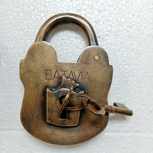 May include: Antique brass padlock with a key, featuring the inscription "BATAVIA" on the front.