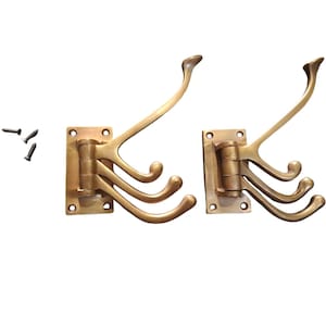 Puede incluir: Dos percheros de latón con cuatro ganchos cada uno. Los percheros están montados en una placa rectangular con tornillos.