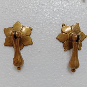 Puede incluir: Dos tiradores de cajón de latón antiguo con un diseño de estrella y un mango en forma de lágrima.