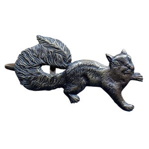 May include: A bronze squirrel figurine with a bushy tail, standing on its hind legs with its front paws raised. The squirrel is depicted in a running pose, with its head turned to the side.