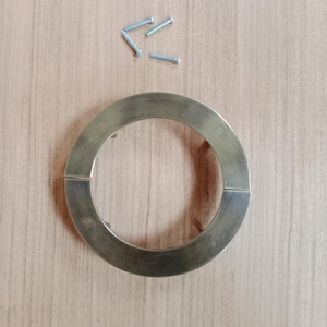 May include: A round, brass door handle with a smooth, polished finish. The handle is split in two sections, with a gap between the two pieces. The handle is shown on a wooden surface with four small screws.