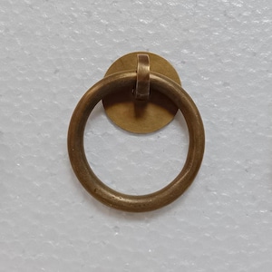 May include: Three brass ring door pulls with a circular backplate. The pulls are a simple design with a smooth finish.