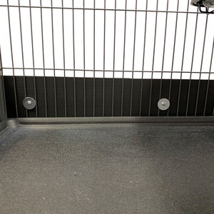 May include: Close-up of the bottom of a black metal cage with a black plastic base. The cage has a black plastic liner around the bottom edge.