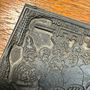 Puede incluir: Un bloque de impresi&oacute;n de metal vintage con una ilustraci&oacute;n detallada de varias figuras con ropa de &eacute;poca. El texto "The Session" es visible al rev&eacute;s. El bloque tiene forma rectangular con intrincados detalles de borde.