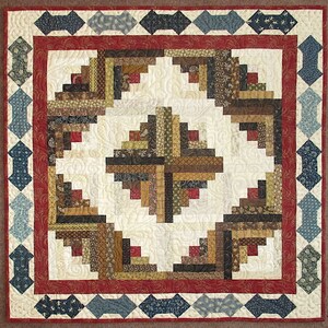 May include: A quilt with a log cabin pattern in shades of brown, tan, and red. The quilt is surrounded by a border of blue and red fabric.