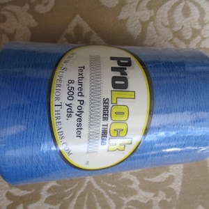 May include: A blue spool of ProLock textured polyester serger thread. The label reads "ProLock Serger Thread, Textured Polyester, 8,500 yds."