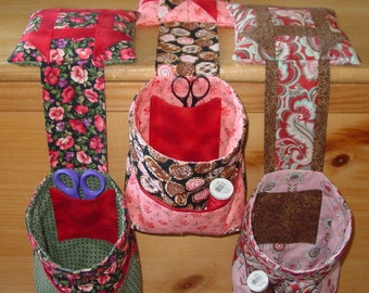 May include: Four hanging fabric storage pockets with red, pink, brown, and green floral patterns. Each pocket has a small square of fabric inside, and some have a spool of thread and scissors.
