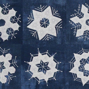 May include: Six different snowflake designs embroidered on a dark blue fabric. The snowflakes are white and have intricate details.