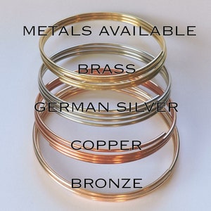 Pu&ograve; includere: Quattro anelli di filo metallico di diversi colori impilati uno sopra l'altro. Gli anelli sono etichettati "Bronzo", "Rame", "Argento tedesco" e "Ottone".