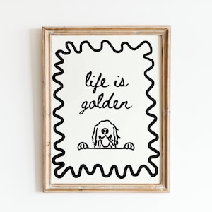 May include: A framed wall art print featuring a black line drawing of a dog peeking over a horizontal line, with the text "life is golden" written above it. The design is enclosed in a black wavy border, all set within a light wood frame.