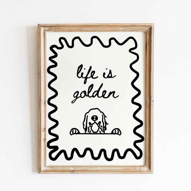 May include: A framed wall art print featuring a black line drawing of a dog peeking over a horizontal line, with the text "life is golden" written above it. The design is enclosed in a black wavy border, all set within a light wood frame.