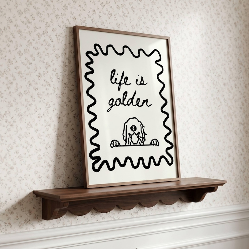 May include: A framed wall art print featuring a black wavy border on a white background. The text reads life is golden in a handwritten script font. Below the text is a simple black line drawing of a dog peeking over a horizontal line.