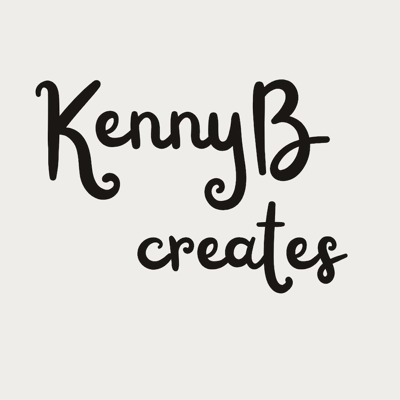 May include: A graphic design featuring the black text KennyB creates in a stylized, cursive script font against a solid, light beige background. The lettering is bold and clear, with the word KennyB positioned above the word creates.