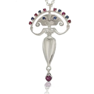 Op de afbeelding: Een zilveren ketting met een hanger met een gestileerde vrouwelijke figuur met een kroon van rode en blauwe edelstenen. De hanger hangt aan een zilveren ketting en heeft een druppel van drie edelstenen.
