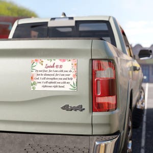 May include: A rectangular car magnet with the text "Isaiah 41:10" and a Bible verse, surrounded by floral illustrations. The magnet is affixed to the rear of a light green pickup truck.