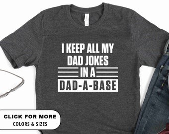 May include: A dark gray t-shirt with white text that reads "I keep all my dad jokes in a dad-a-base".
