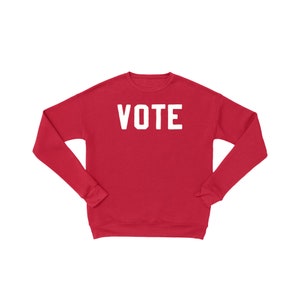 Peut inclure: Sweat-shirt rouge avec le mot "VOTE" imprim&eacute; en blanc sur le devant.