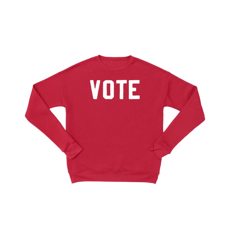 Peut inclure: Sweat-shirt rouge avec le mot "VOTE" imprim&eacute; en blanc sur le devant.
