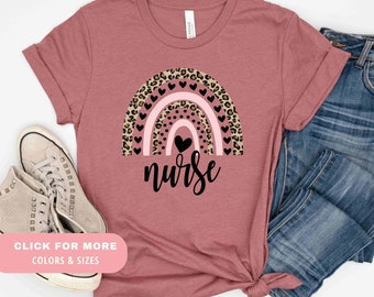 May include: A mauve t-shirt with a rainbow design featuring leopard print and pink hearts. The text "nurse" is written below the rainbow.
