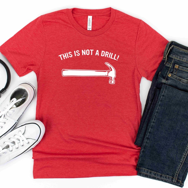 May include: Red t-shirt with white text that says "This is not a drill!" and a white outline of a hammer.