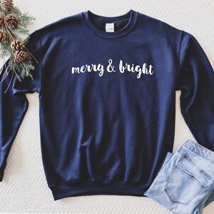 May include: A navy blue sweatshirt with the text "merry & bright" in white lettering.