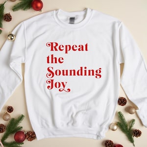 May include: White long-sleeved sweatshirt with red text that reads "Repeat the Sounding Joy".