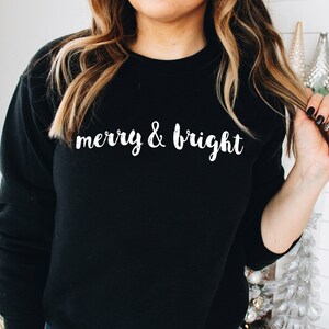 May include: Black sweatshirt with white text that reads "merry & bright".