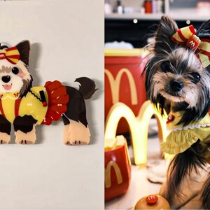 May include: A small brown and black dog wearing a yellow and red outfit with a red bow on its head. The dog is standing on a white background.