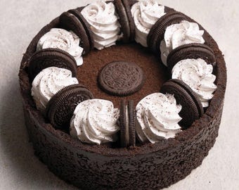 May include: A chocolate cheesecake with a chocolate cookie crust, topped with whipped cream and Oreo cookies.