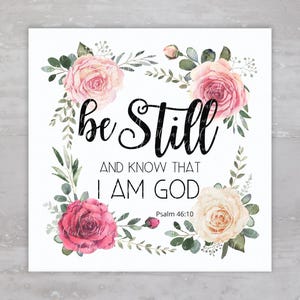 May include: A white background with a floral wreath surrounding the text "be still and know that I am God" with the scripture reference "Psalm 46:10".