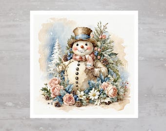 以下が含まれることがあります： 青い帽子とマフラーをつけた雪だるまの水彩画。雪だるまはピンクのバラ、白い花、緑の葉に囲まれている。